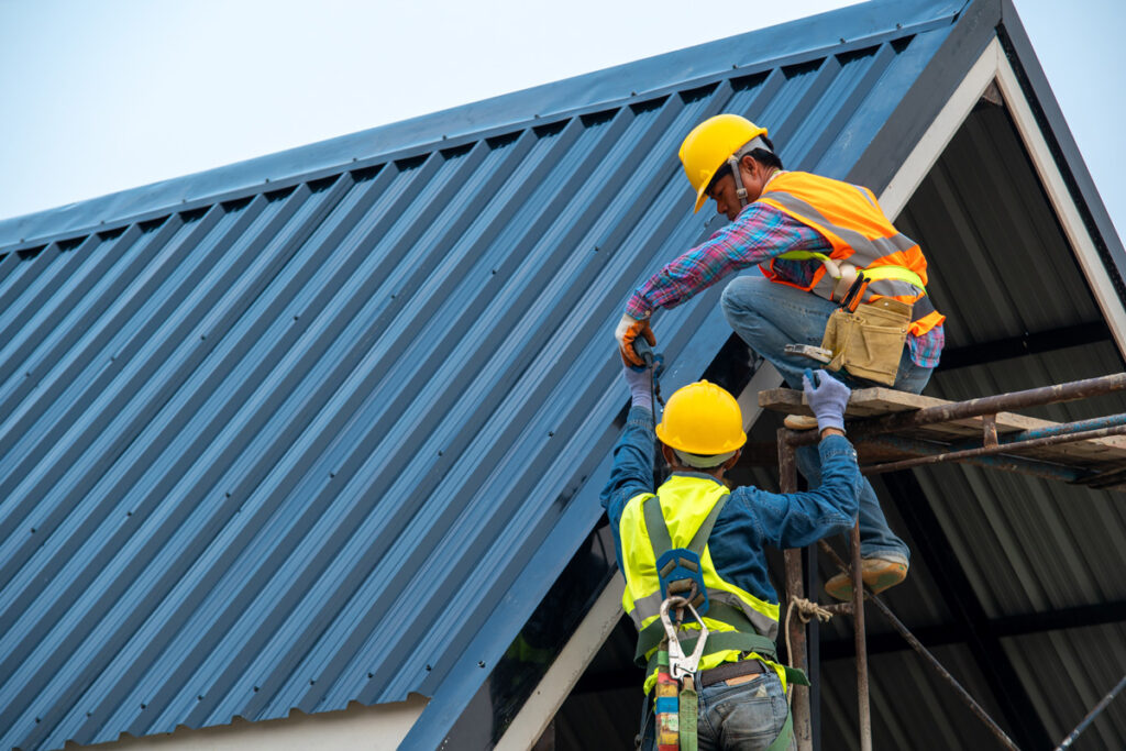 Two people are installing r-panels on a roof in El Paso.